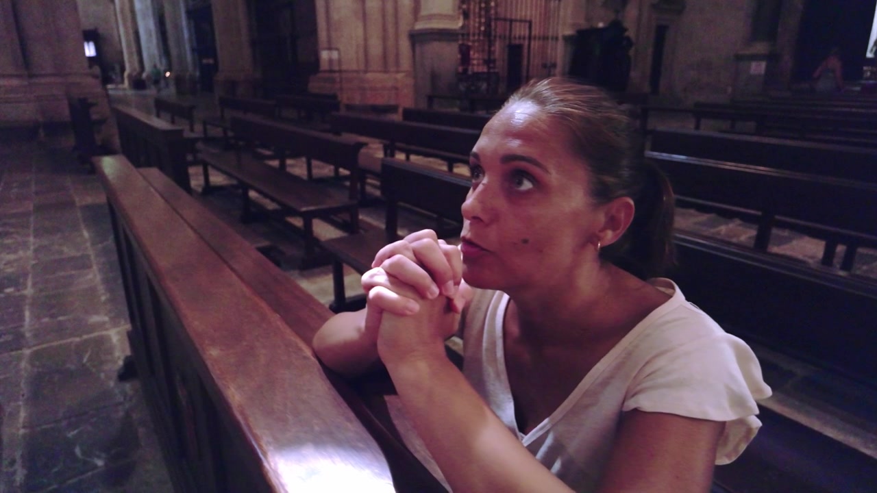 Mulher orando com as mãos postas na Catedral de Tarragona