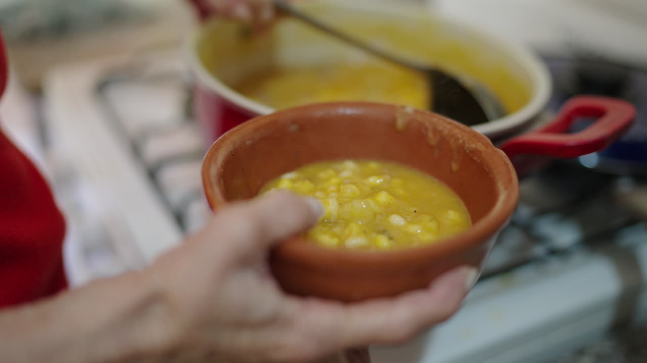 Serving spoon dips into finished Argentinian locro showing beans, corn, and meat