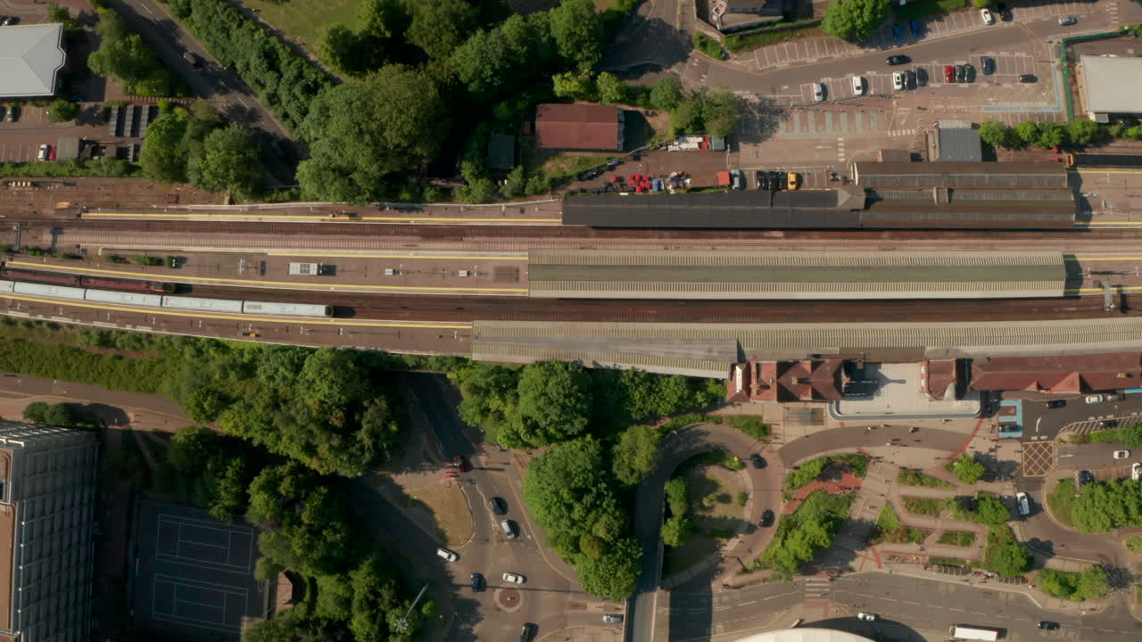 Top down aerial shot over trains leaving a small town train station UK Basingstoke