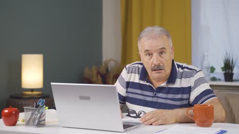 Home office worker old man looking at camera confused.