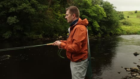 disparo en primer plano de un pescador de mosca en waders lanzando su línea en un río