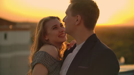 due amanti un uomo e una donna ridono e ballano sul tetto al tramonto. slow motion coppia felice estate sul tetto.