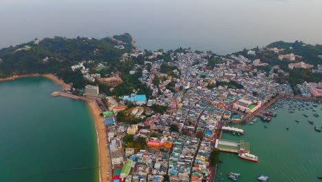 Drone-shot-traveling-backward-of-a-city-built-on-an-isthmus-with-an-harbor-and-a-popular-beach-during-the-day