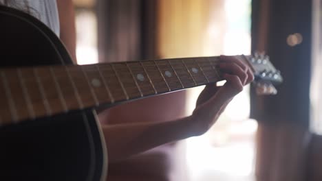 close up view of a girl's playing an acoustic guitar in a home studio.