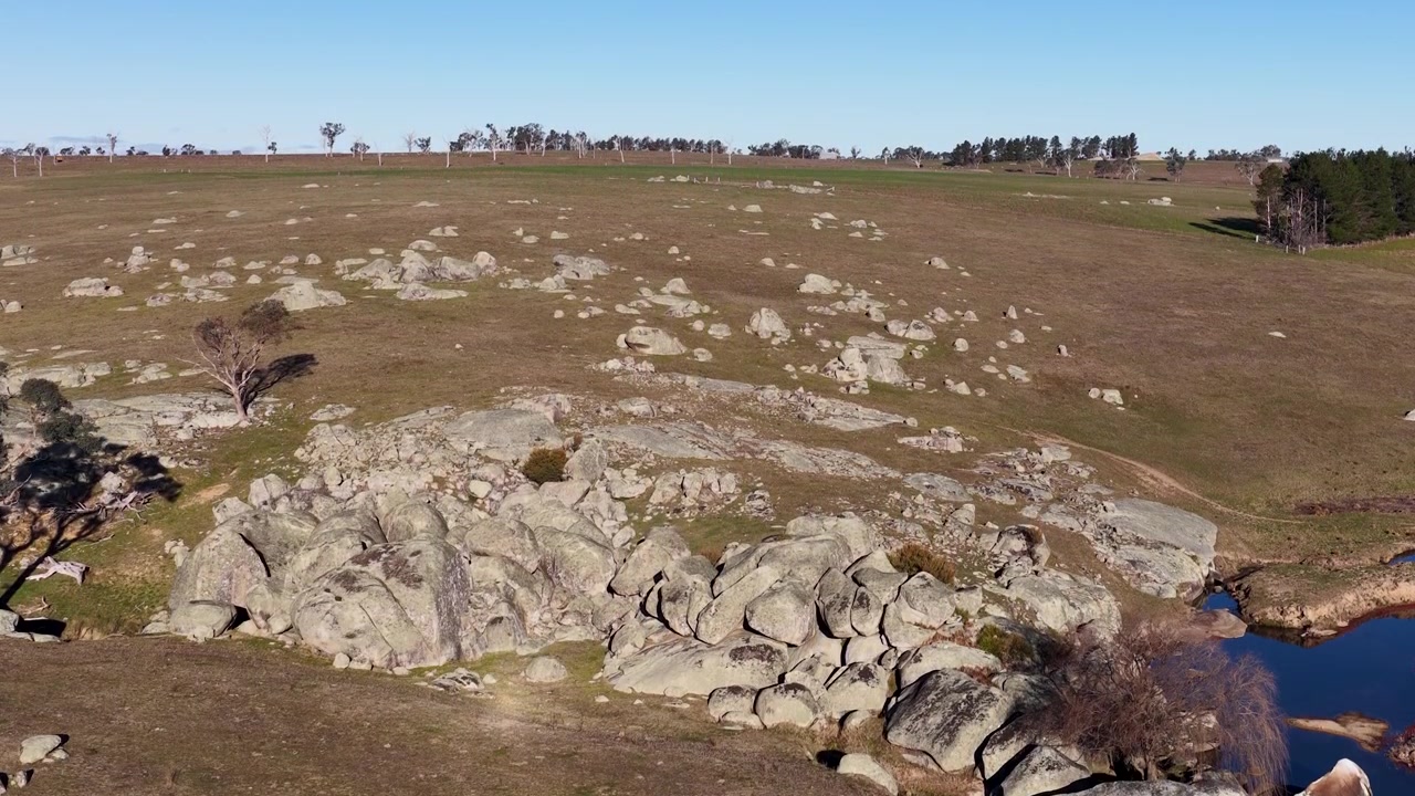 Ripresa con drone di affioramenti rocciosi e un ruscello serpeggiante nella Nuova Galles del Sud rurale, Australia