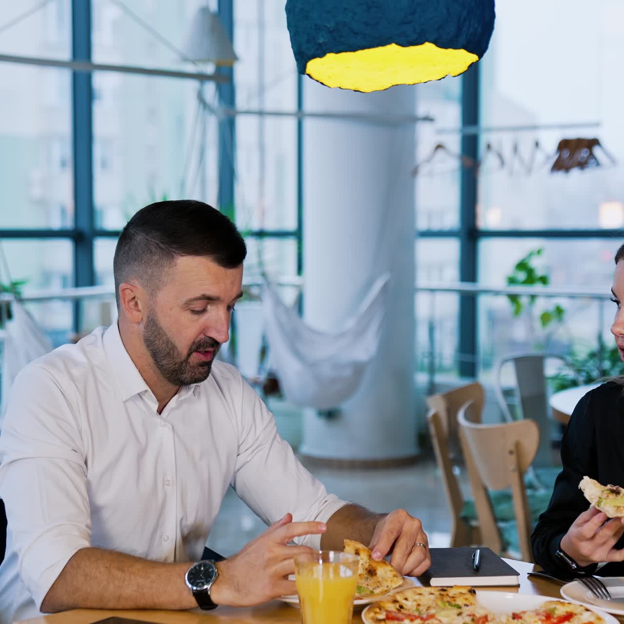 Colleagues having pizza at during lunch break. Man and woman sit in café and discuss issues