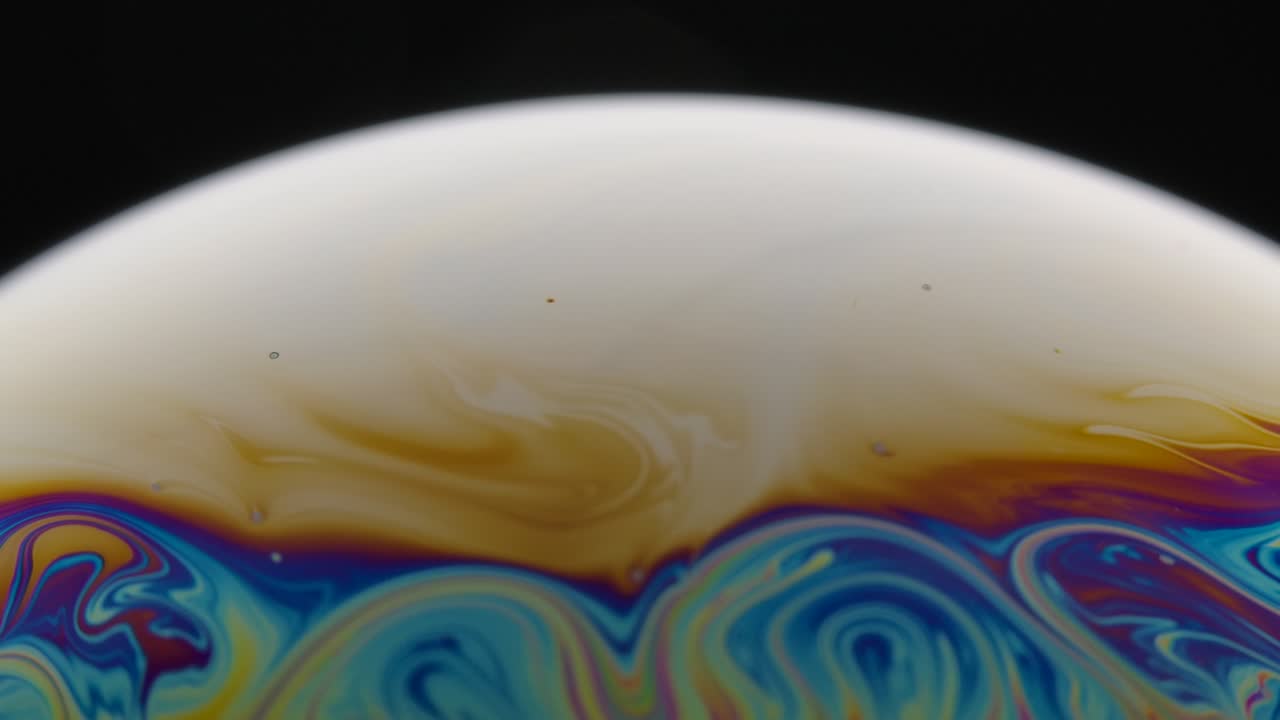 una toma macro de la superficie de una película delgada de jabón con colores de arco iris que crea un hermoso efecto de remolino. semicírculo de una burbuja de sabón con rayas de colores en un fondo negro. primer plano. cámara lenta