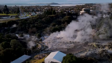 beautiful aerial over te puia’s pohutu geyser reveal of scenery rotorua lake on horizon during golden hour