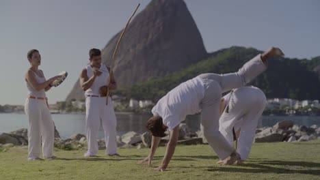 people practicing capoeira with sugarloaf mountain in the background