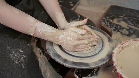 a woman potter makes dishes from clay. a woman makes a jug on a potter's wheel