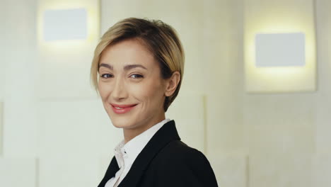 close-up view young caucasian blonde businesswoman in formal clothes looking at the camera and smiling in a meeting room