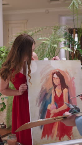 modelo en vivo con el cabello suelto mira el retrato en el caballete. joven con vestido rojo es testigo de la habilidad y creatividad del artista manifestándose en el lienzo en el estudio de arte