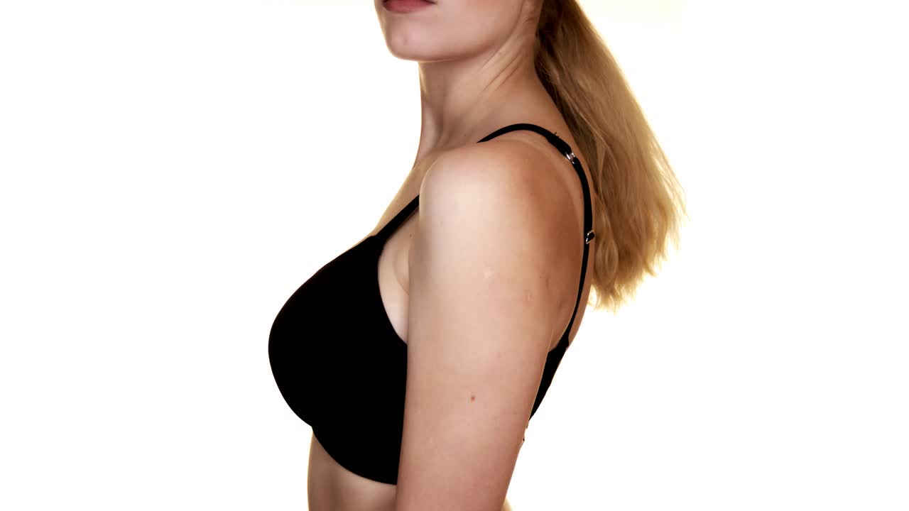 Close-up side view of a young woman in a black bra
