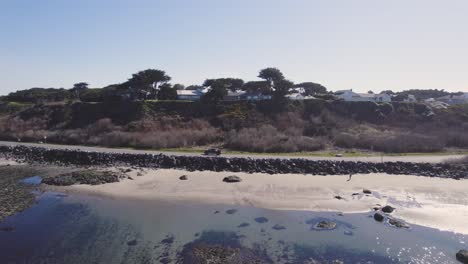 aerial tracking shot follows suv drive along sunny coastal road with view of rocky beach