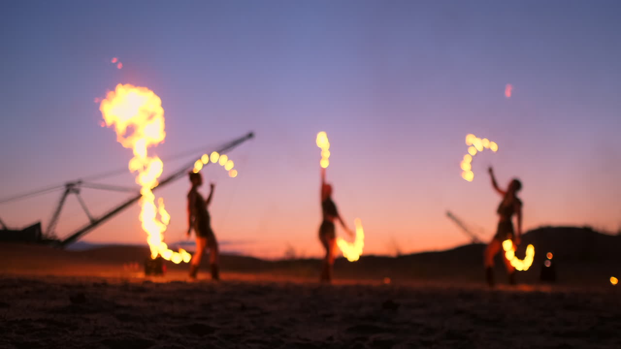artistas profesionales muestran un espectáculo de fuego en un festival de verano en la arena en cámara lenta. acróbatas de cuarta persona del circo trabajan con fuego por la noche en la playa