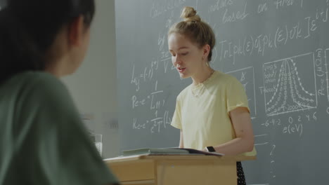 a woman lecturing in front of a chalkboard in a classroom