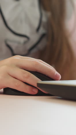 little girl moves computer mouse using laptop with brother at table closeup. schoolgirl with classmate do digital tasks on internet lesson at home