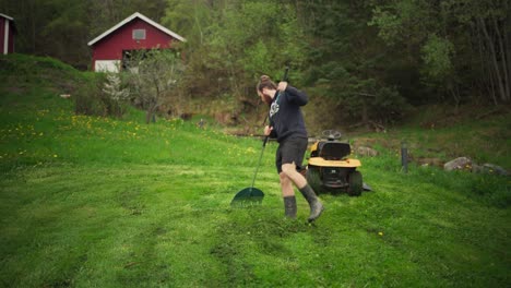 a man is raking grass in a green lawn