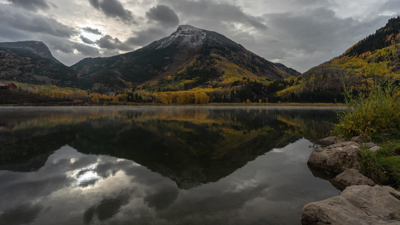 Timelapse Of Stormy Clouds Above Crystal Lake and Mountain Hills in Autumn Colors