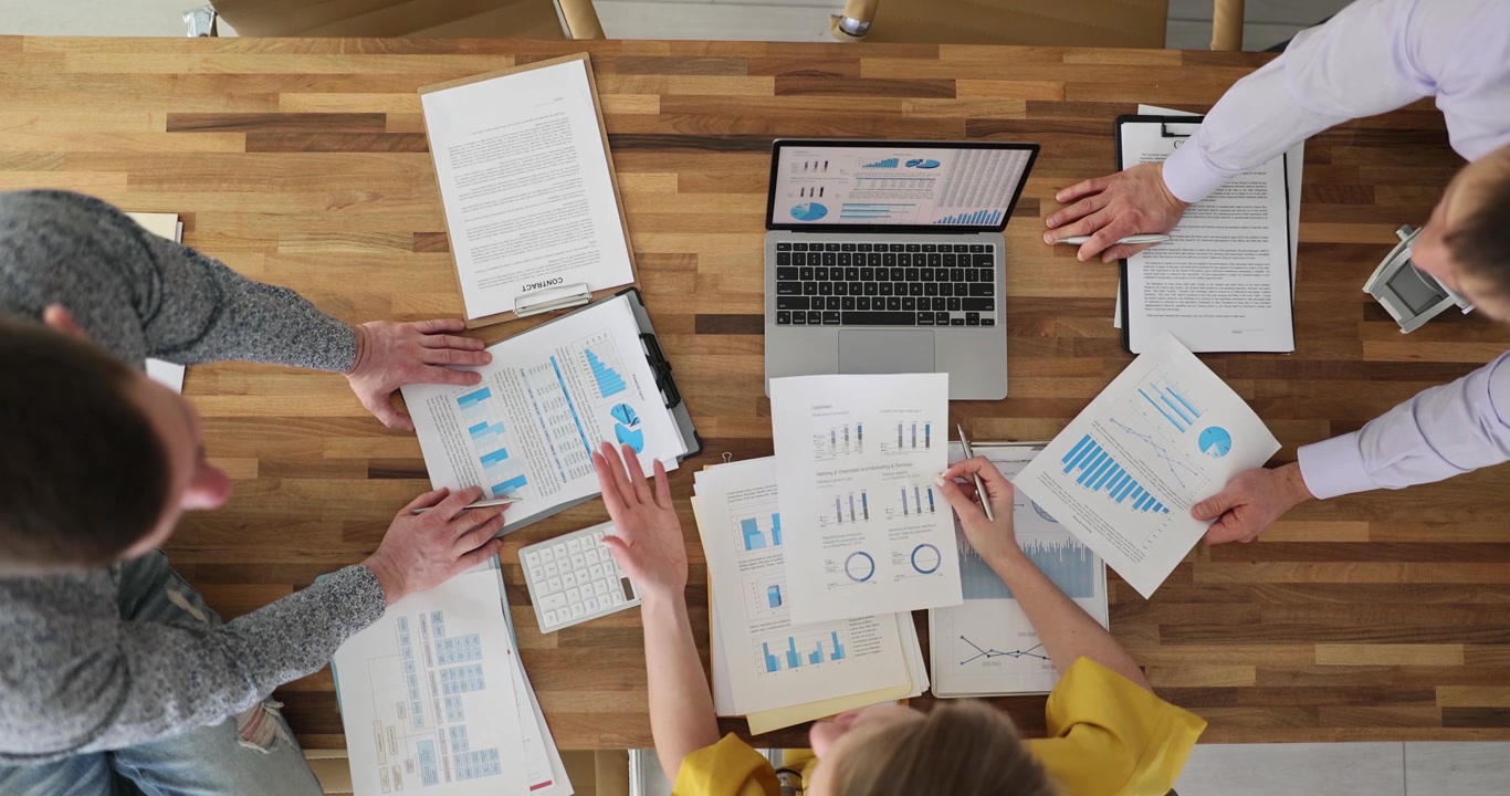 Colleagues discuss business data studying charts at desk