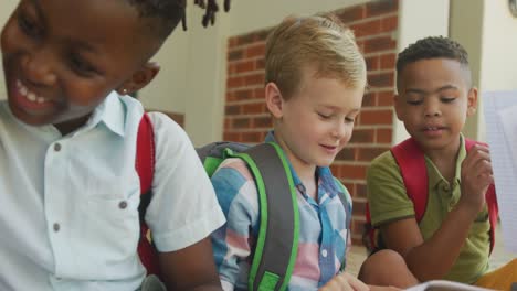 video de niños felices y diversos sosteniendo libros y hablando frente a la escuela