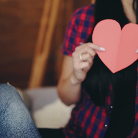girl is showing ready carved heart from colored paper for Valentine's Day