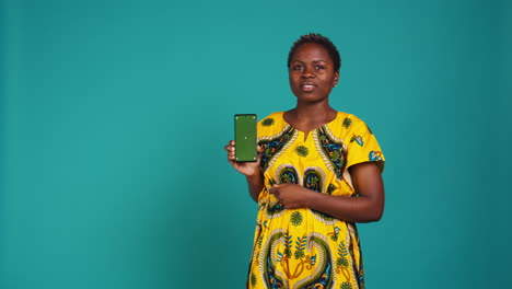 Young-confident-woman-presenting-a-green-screen-on-smartphone