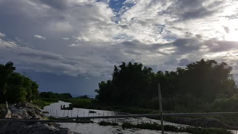 Water-buffalo-bathing-afar-on-a-shallow-stream-surrounded-by-trees-and-thick-clouds-in-the-Philippines