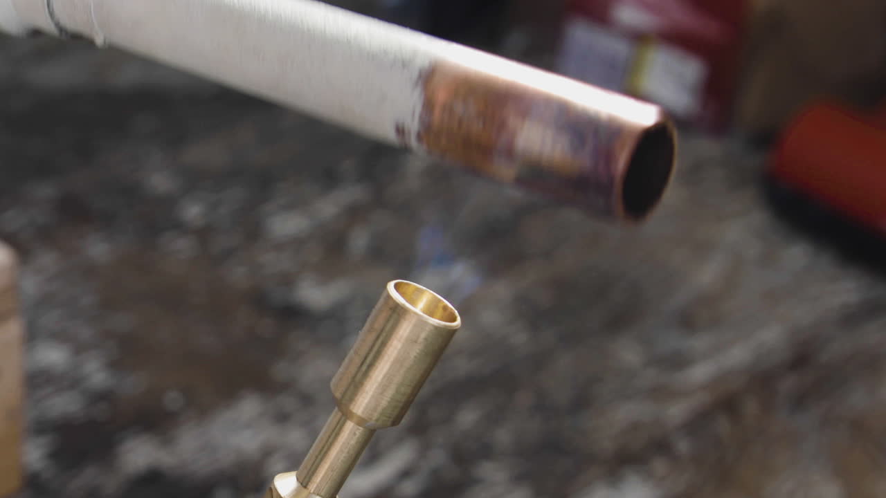 una gota de agua caliente sale disparada de un tubo de cobre mientras se calienta con un soplete de propano