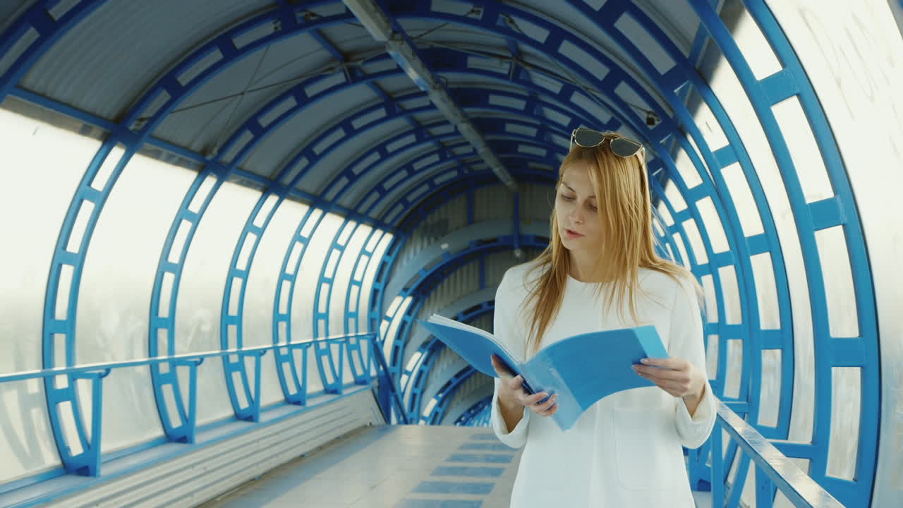 mujer de negocios caminando lentamente sobre la transición de vidrio moderna siguiendo en la carpeta de documentos