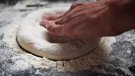 chef estirando masa fermentada con harina para una pizza casera