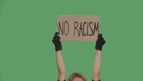 the hands of an unknown person in black gloves raise a cardboard poster no racism. plurality of violence and anti black racism. isolated a green screen, chroma key. close up. slow motion