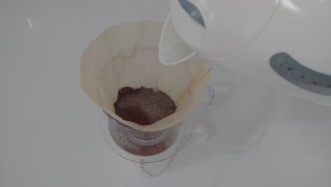 Hand-pour-over-hot-water-to-the-coffee-for-extracting-and-making-drip-black-coffee