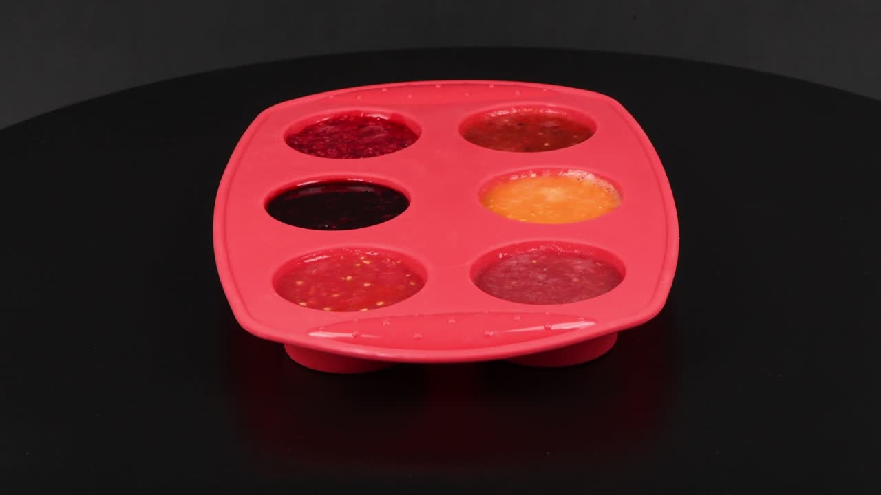 congelar batido de frutas en molde de silicona sobre fondo negro. vista lateral. movimiento en bucle. rotación 360.