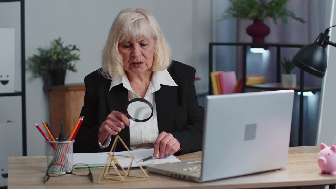 mujer de negocios sénior mira a través de una lupa, investigar, analizar, leer documentos