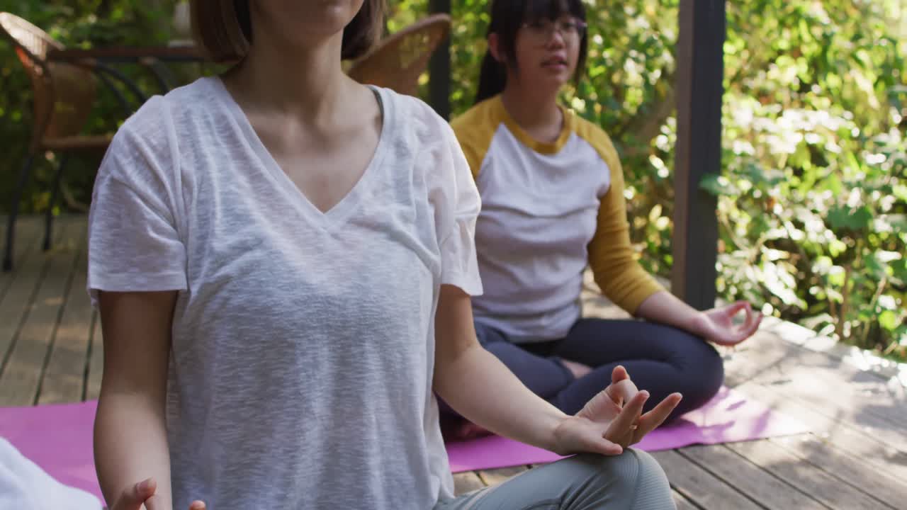 madre y hija asiáticas meditando juntas en el jardín