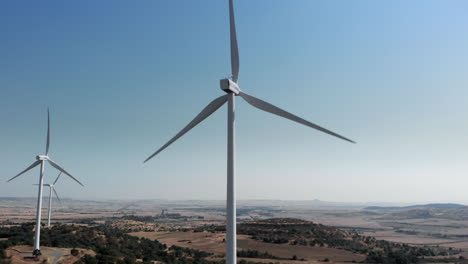 drone orbits wind turbines in rural area on sunny day tilts up at end