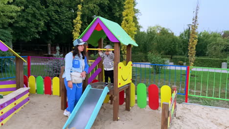 mom and her active toddler son at the playground. mother comes up to the child and fixes his clothes.