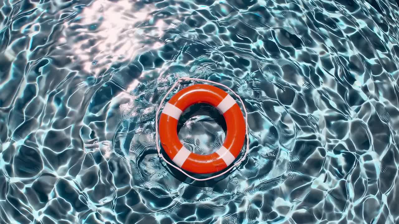 Overhead video shot of a vibrant pool with a lifebuoy. The rippling water creates a dynamic