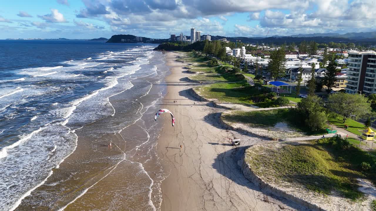 Aerial footage captures beach erosion along Gold Coast, Australia, with visible waves, kite surfers, and coastal landscape under bright sunlight