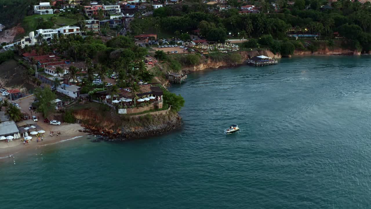 Dolly in tilt down aerial drone shot approaching the famous sunset lookout from the Guara&iacute;ras Lagoon in the tropical beach town of Tibau do Sul in Rio Grande do Norte, Brazil during dusk