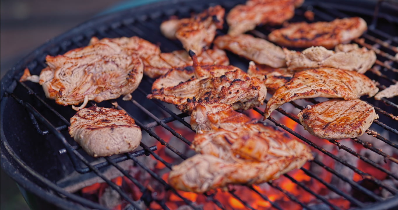 A slow lateral move reveals chicken gaining color over glowing charcoal as it is turned by hand, full of smoke, warmth, and the unmistakable texture of real homemade grilling.