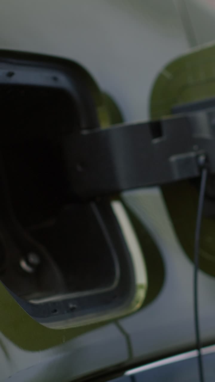 Vertical video Close up of person opens vehicle inlet port of EV eco friendly car to charge it