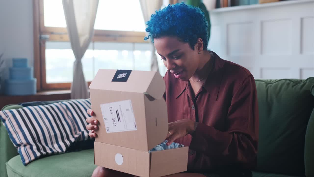 Young overjoyed african american woman unpacks box and screams with happiness