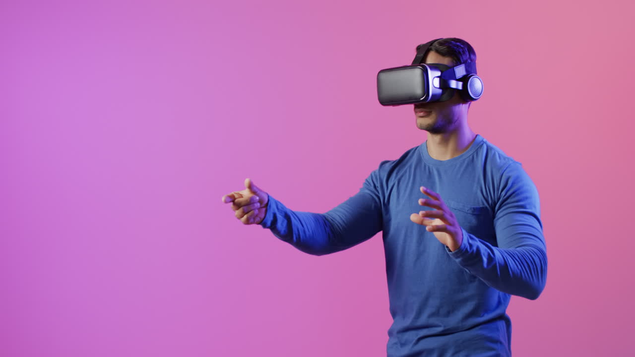 video di un uomo biraciale che usa le cuffie vr su sfondo rosa e viola