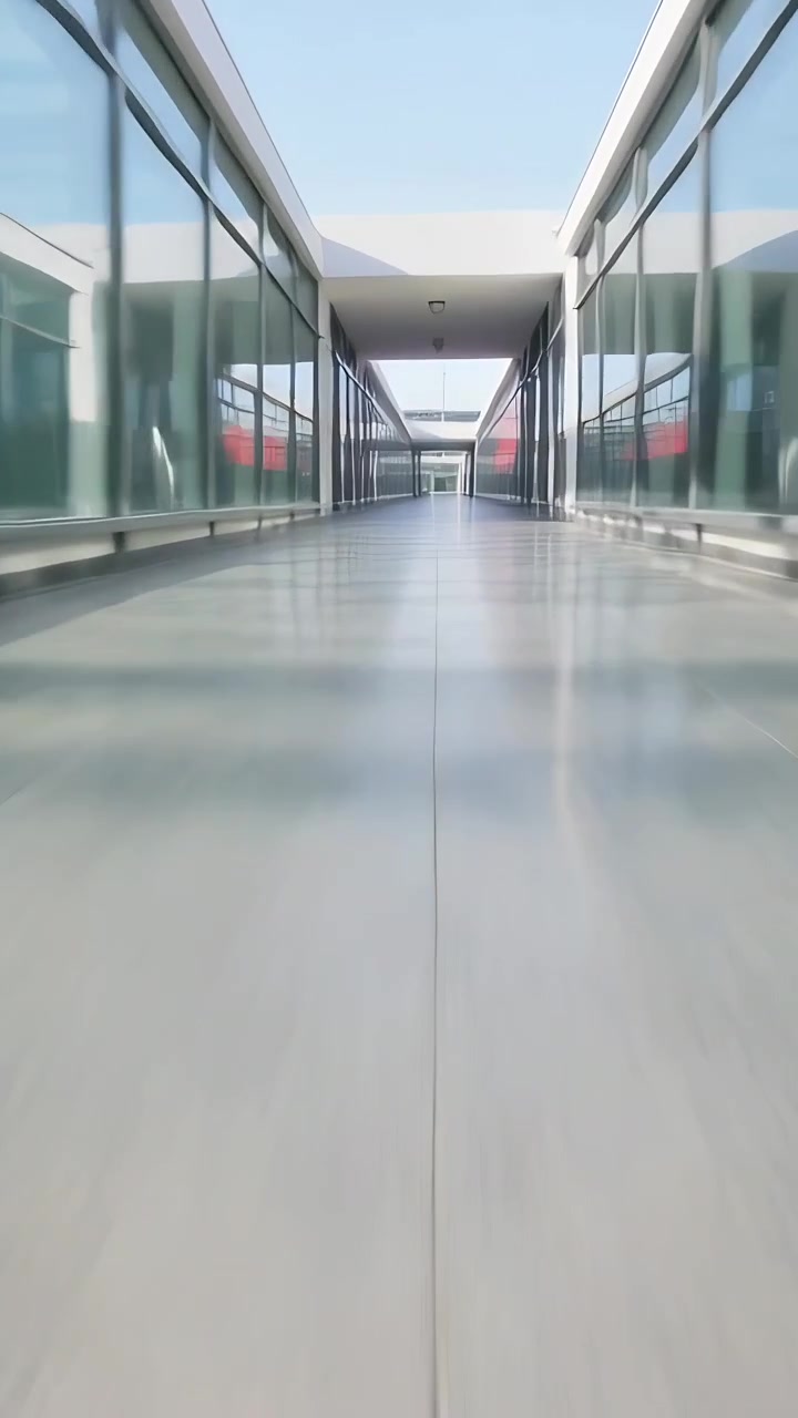 Video vertical: Operador moviendo la cámara hacia adelante a lo largo de un puente hacia una puerta, mostrando paneles de vidrio, junta.