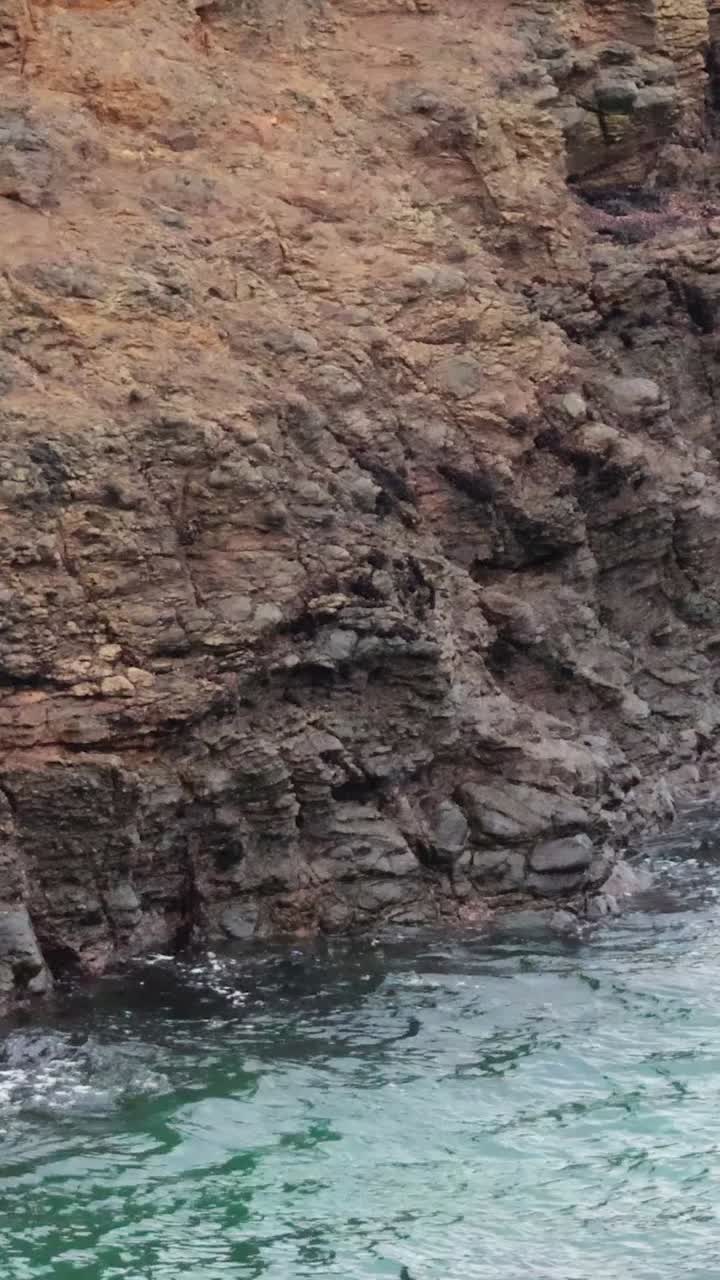 una vista serena de las olas golpeando suavemente acantilados rocosos a lo largo de la gran carretera del océano, capturado en la luz natural del día
