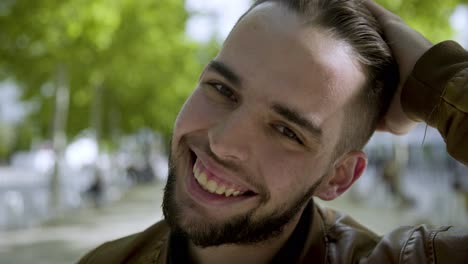 closeup shot of smiling young man winking while looking at camera.