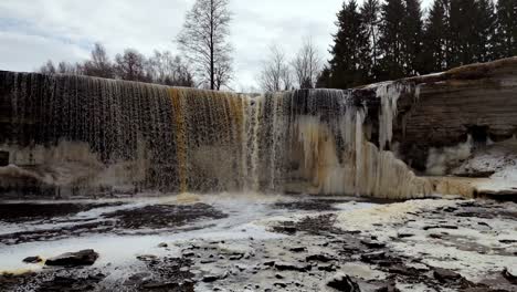 aerial drone fly dam waterfalls in cold frozen autumn slow motion water fall dry trees skyline background