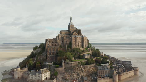 Amplia-Vista-Del-Castillo-De-Le-Mont-Saint-Michel-En-El-Océano-En-Francia,-Aéreo,-Nublado